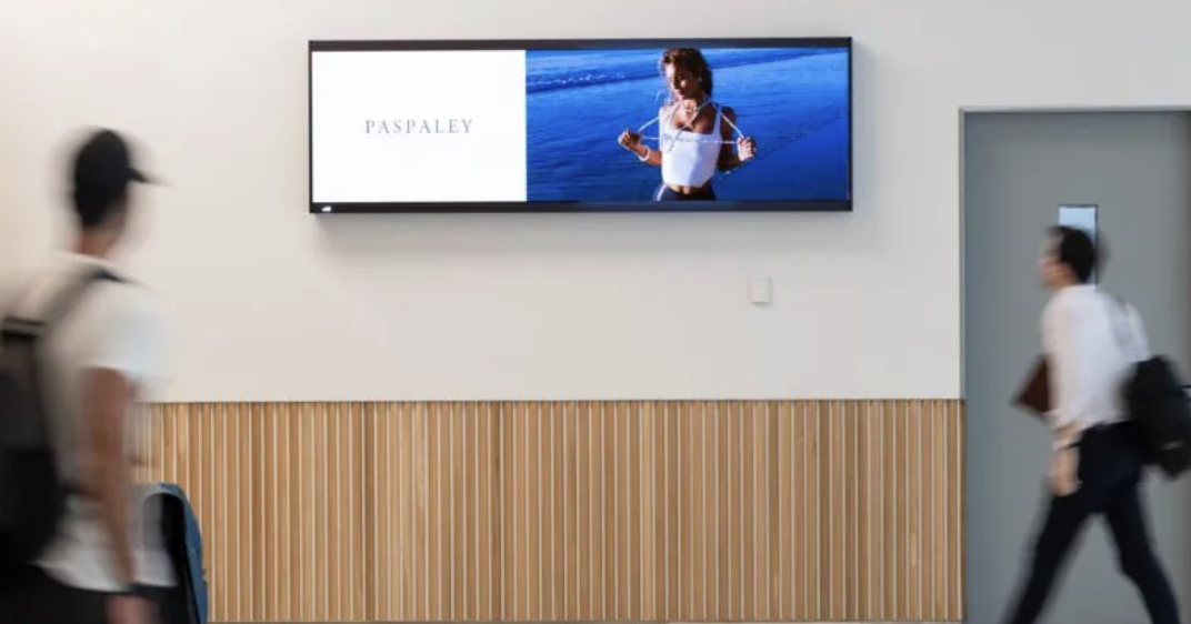 Ultra-wide stretch screen mounted in a members lounge corridor
