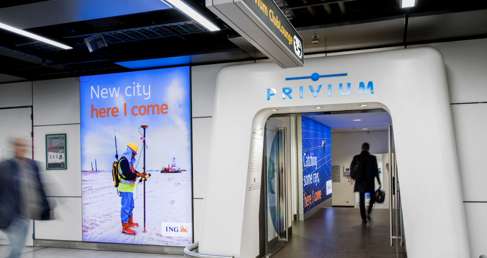 Illuminated advertising panel beside a members-only club lounge entrance